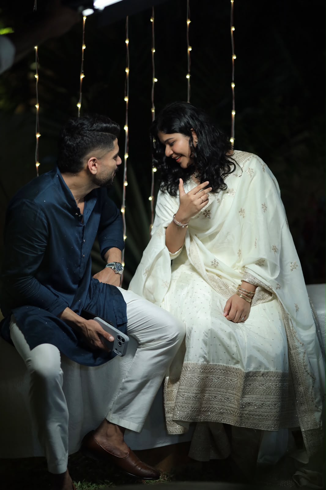 Shaheel and Nasila seated together beneath string lights